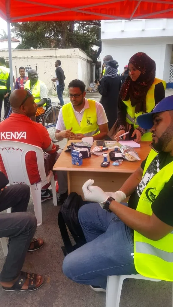 Volunteers in reflective vests screening people for diabetes and blood pressure at a community health walk