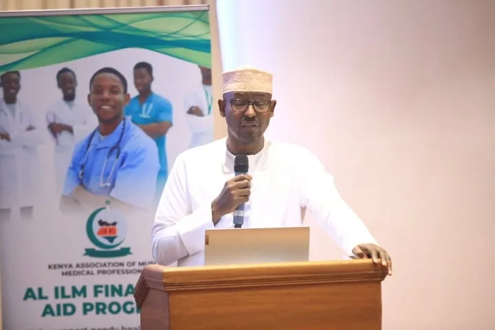 A speaker presents the Al Ilm Financial Aid Program beside its banner at the 7th KAMMP Scientific Conference, 2025