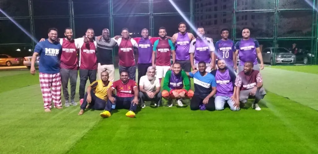 Two football teams lined up together on the pitch after a match