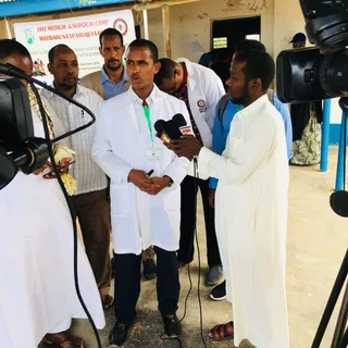 Doctors in white coats speak to the press at the free medical and surgical camp in Garissa, 2018