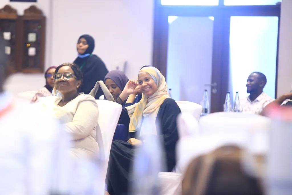 Delegates at a session table, the hall bright with daylight, 2025