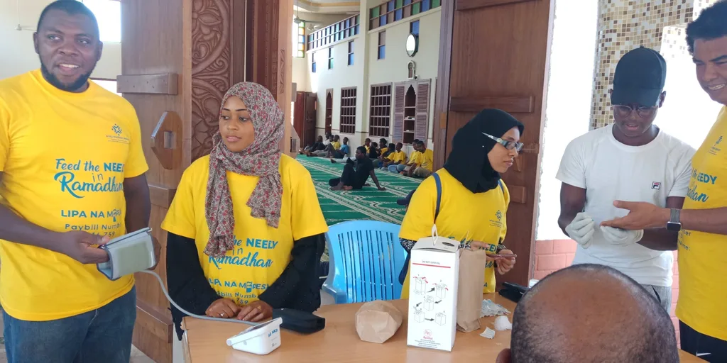 Volunteers with a blood pressure monitor at the KAMMP community health day, 2019