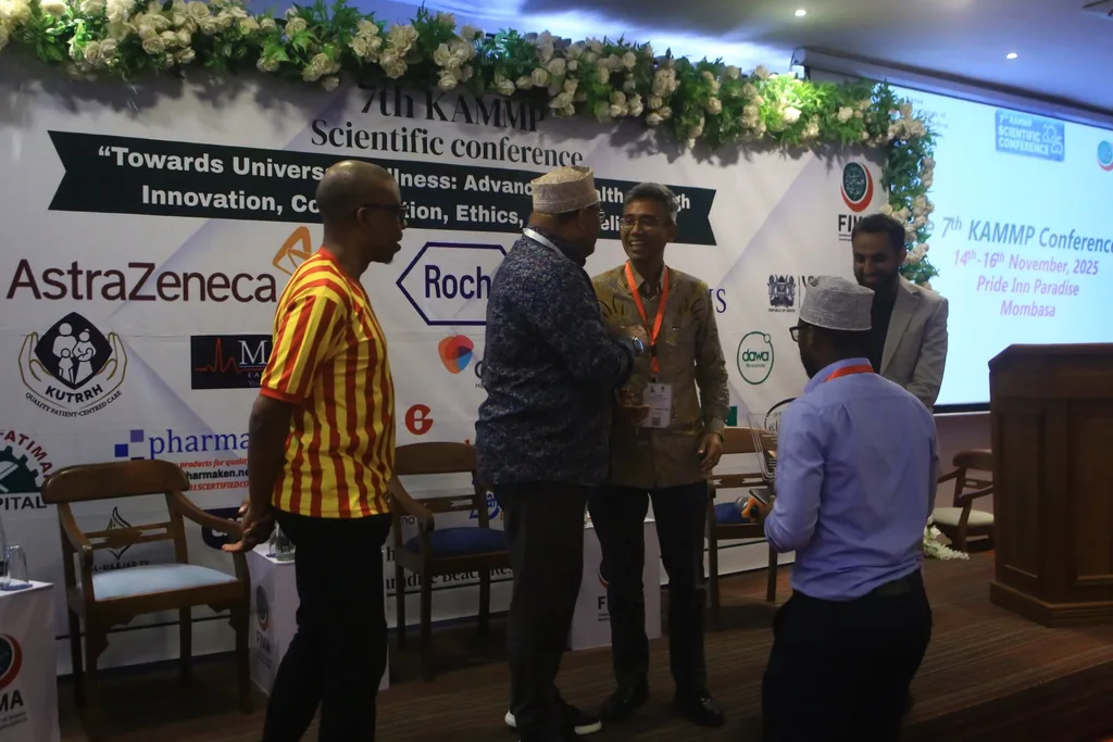 Delegates talking in front of the 7th KAMMP Scientific Conference banner between sessions, 2025