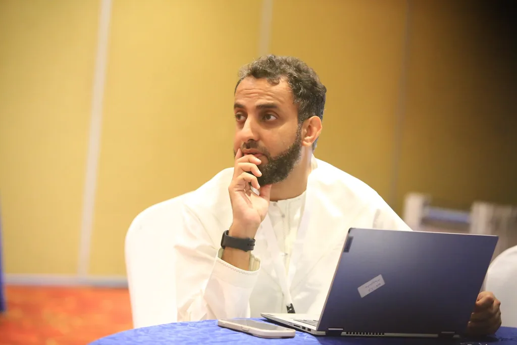 A delegate with a laptop follows a session at the 7th KAMMP Scientific Conference, 2025