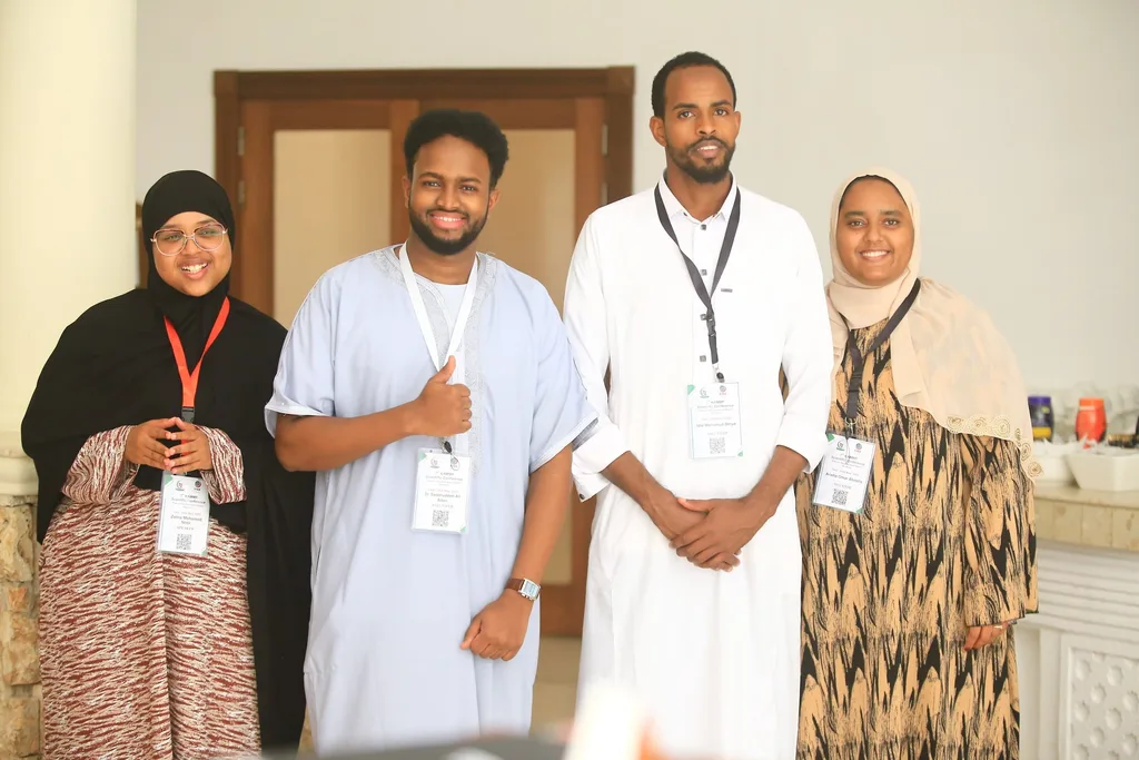 Four delegates with their conference badges smiling together at the 7th KAMMP Scientific Conference, 2025