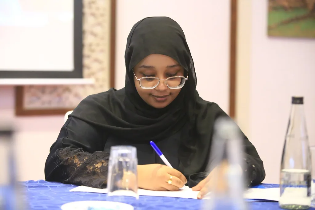 A delegate taking notes during a session of the 7th KAMMP Scientific Conference, 2025