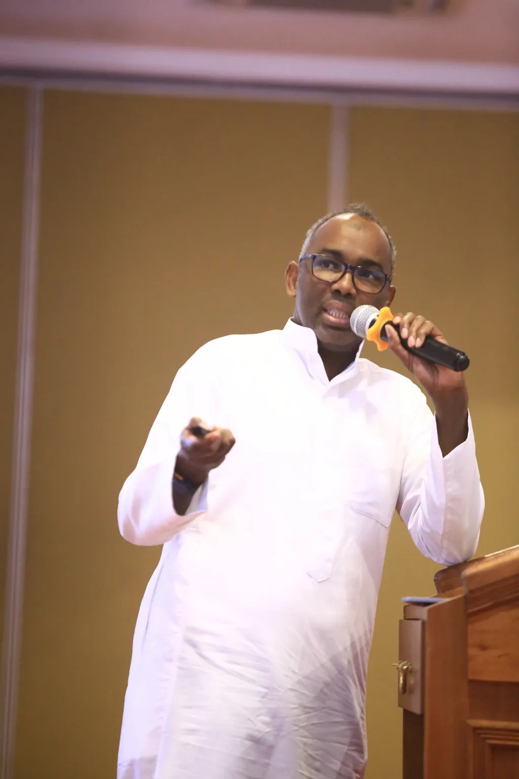 A speaker addresses the hall with a microphone at the 7th KAMMP Scientific Conference, 2025